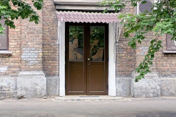 Fototapeta na wymiar brown closed glazed door on the brick wall of the house on the street