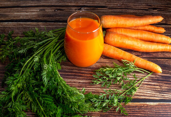 Fresh-squeezed carrot juice on a wooden background
