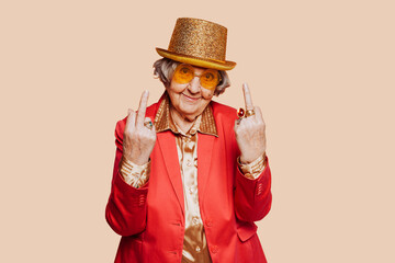 Funny smiling elderly grandmother portrait showing middle finger gesture with hand at studio....