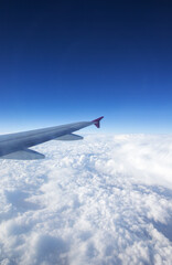 Aerial view of cloud blue sky and plane wing view through the airplane window.