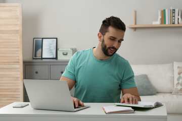 Fototapeta premium Online test. Man studying with laptop at home