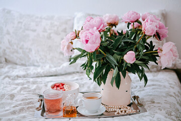 Tray with bouquet of pink peonies flowers and a cup of black coffee and Breakfast in bed, summer morning concept. Healthy food