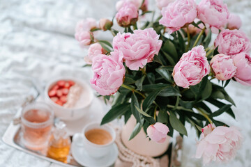 Obraz na płótnie Canvas Tray with bouquet of pink peonies flowers and a cup of black coffee and Breakfast in bed, summer morning concept. Healthy food