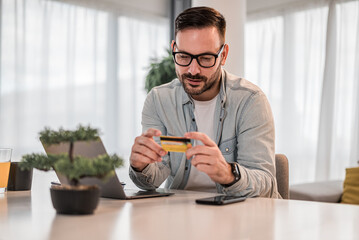 Thoughtful businessman analyzing credit card while doing payment at office