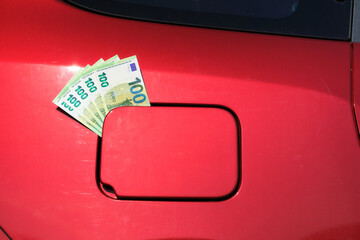 A bundle of one hundred euro notes sticking out of a car's fuel tank lid.