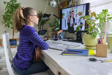 Child girl studying at home online using computer