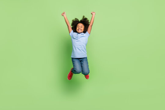 Full length body size view of beautiful cheerful pre-teen girl jumping having fun isolated over green color background