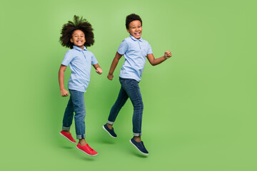 Full length body size view of trendy cheerful pre-teen friends friendship jumping strolling isolated over green color background