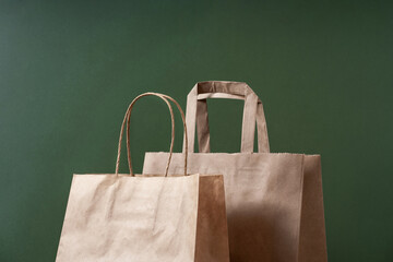 Kraft paper recycled shopping bag on green background minimal concept. Sustainable packaging...