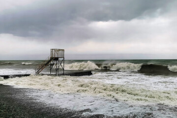 Rescue tower on the seashore during a storm. Waves, wind, clouds.