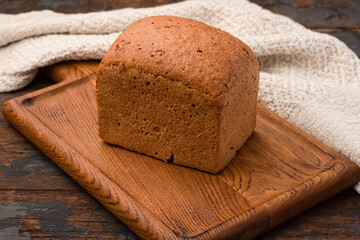 Bread, baguette, boton, rye on a wooden background.