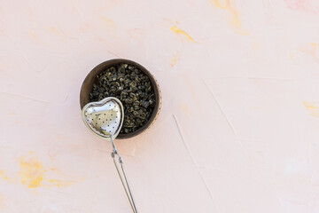 Chinese high quality gunpowder loose leaf tea. Jasmine Green tea leaves rolled in tight spiral. Green snail tea balls in wooden bowl on pink background. Dragon pearl Jasmine Green snail tea balls and