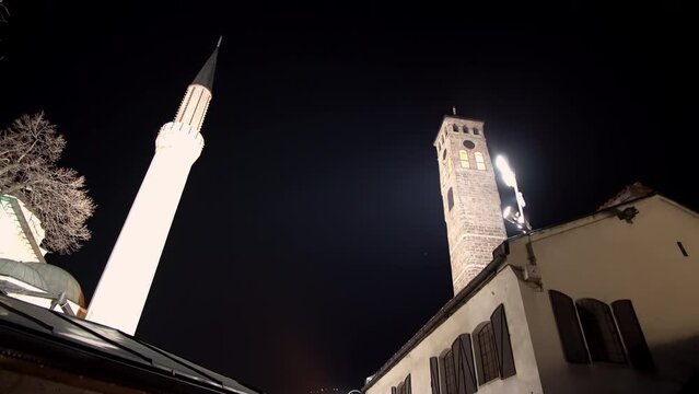 Architectural detail of the old clock tower and minaret of Gazi Husrev beg mosque at night in Sarajevo, Bosnia and Herzegovina