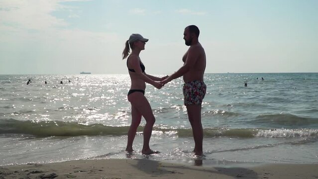 Young happy couple in love having romantic tender moments on the sandy tropical beach. Summer vacation amd love concept. Slow motion
