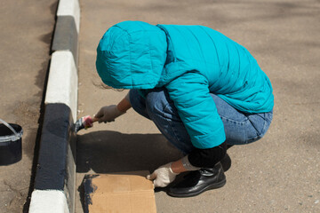 The girl paints the border. Saturday clean-up in Russia.