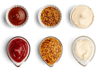 Mustard, mayonnaise, ketchup in ceramic and glass gravy boats. Top view of three sauces isolated on white background.