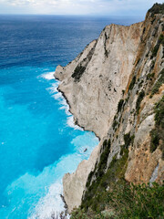 Storm waves crash against the cliffs near shipwreck Navagio beach Zakynthos Greece. Top view of bright blue turquoise sea waters with grey rocks