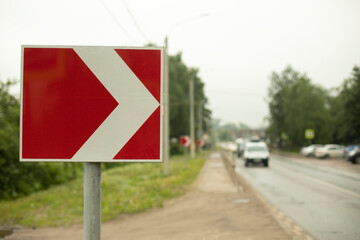 Sign sharp turn. Red road sign. Arrow pointer on road.
