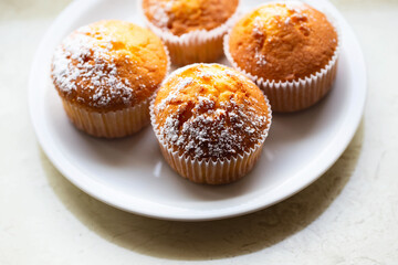 Sweet muffins with powdered sugar and blossoms. Homemade bakery. Muffins in white capsules decorated with fruit tree flowers.