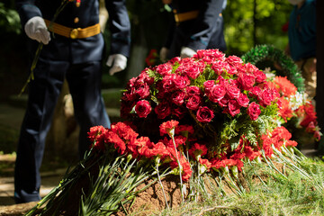 Flowers on grave. Military lay flowers on grave of soldier. Details of ceremony.