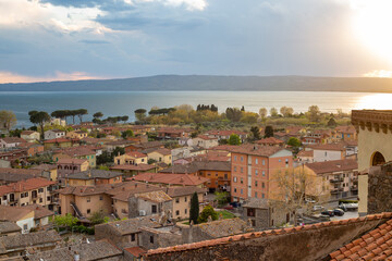 Fototapeta na wymiar Panoramic view of the old famous city of Bolsena and Lake Bolsena at sunset. Province of Viterbo, Italy, Lazio. Cityscape and tiled roofs