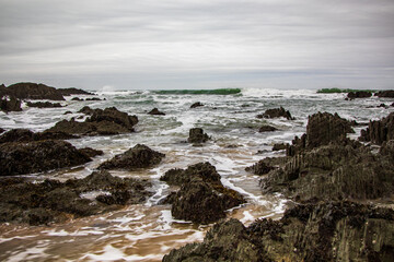 Fototapeta na wymiar The sea laps the rocks on the beach, as the next big waves roll in on the North Devon Beach.