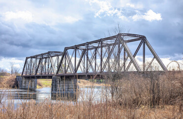 Fototapeta na wymiar Old iron railway truss bridge built in 1893 crossing the Mississippi river in spring in Galetta, Ontario, Canada