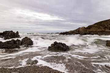 Dark rocks on this Devon Beach, being washed by the waves, as they have been every day for millennia.