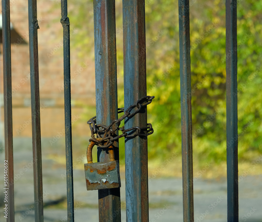 Poster the old gates of the factory are locked with a rusty old chain around them. an old metal gate with a