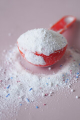 Washing powder in plastic spoon on blue background 