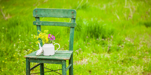 Dekoration mit einem alten Stuhl und einer Kaffekanne in einem Natur Garten