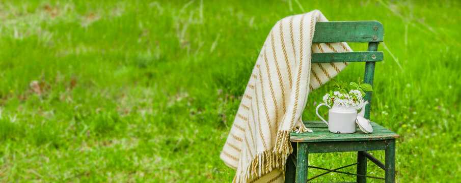 Dekoration mit einem alten Stuhl und einer Kaffekanne in einem Natur Garten