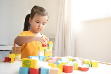 Asian baby girl playing alone. Little kid plays building blocks.