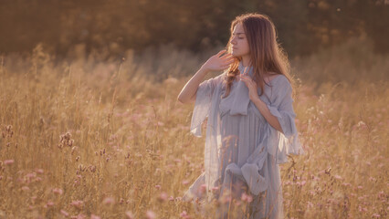 Portrait of a girl with long hair in a blue dress on the background of nature