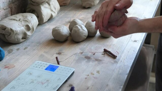A potter combines two pieces of clay into one large lump.