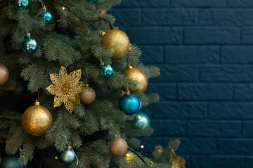 Closeup of Festively Decorated Outdoor Christmas tree with blue and golden balls on blurred sparkling fairy background. Defocused garland lights