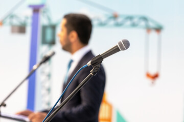 Public speaking or relations with copy space concept. Microphone in focus, blurred unrecognizable...