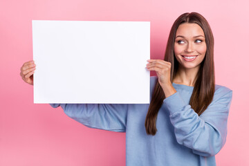 Portrait of attractive cheerful girl holding copy blank space banner promoter ad isolated over pink pastel color background