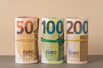 Euro in rolls background. Fifty, one hundred and two hundred euro bills are rolled up. European paper banknotes. Financial and money saving concept.