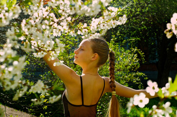Girl with long hair among cherry blossoms in the garden. Spring