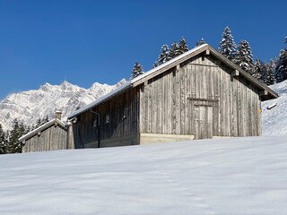 Indigenous alpine huts and wooden cattle stables on Swiss pastures covered with fresh white snow cover, Nesslau - Obertoggenburg, Switzerland (Schweiz)