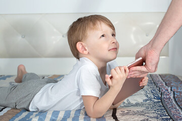 Kids and gadgets. The child does not want to give the tablet to his parents.