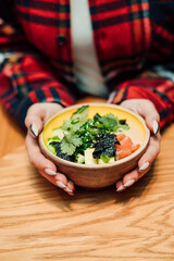 Delicious salad of tomatoes and greens in a deep plate and hands of a woman