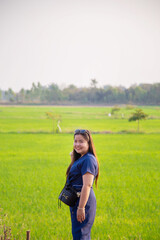 Portrait smiling Asian woman in blue casual wear standing in front of rice field