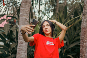Non-binary person taking a selfie with a cell phone 

