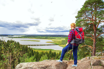 Naklejka premium Young woman tourist with a backpack on the top of the mountain.