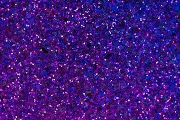 Abstract glitter background with blue-violet neon illumination. Trendy sparkling backdrop with copy space. Shiny Glitter close-up with particles.