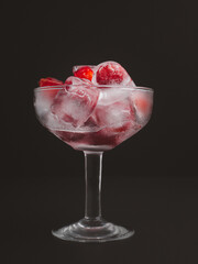 Wine glass with a fresh cherry on ice. Refreshing cold drink