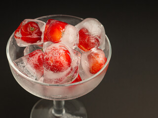Wine glass with a fresh cherry on ice. Refreshing cold drink