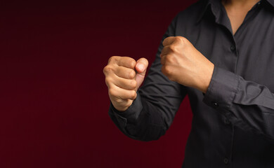 Businessman in a black shirt raised his fist air while standing on a red background